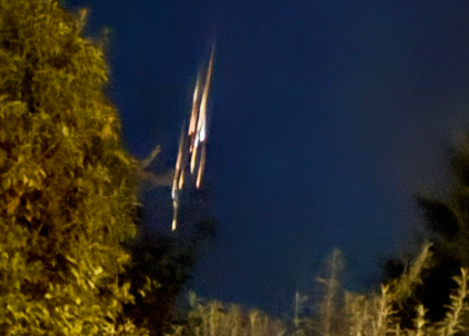 Plusieurs trainées rougeoyantes et parallèles sur fond de ciel bleu nuit.