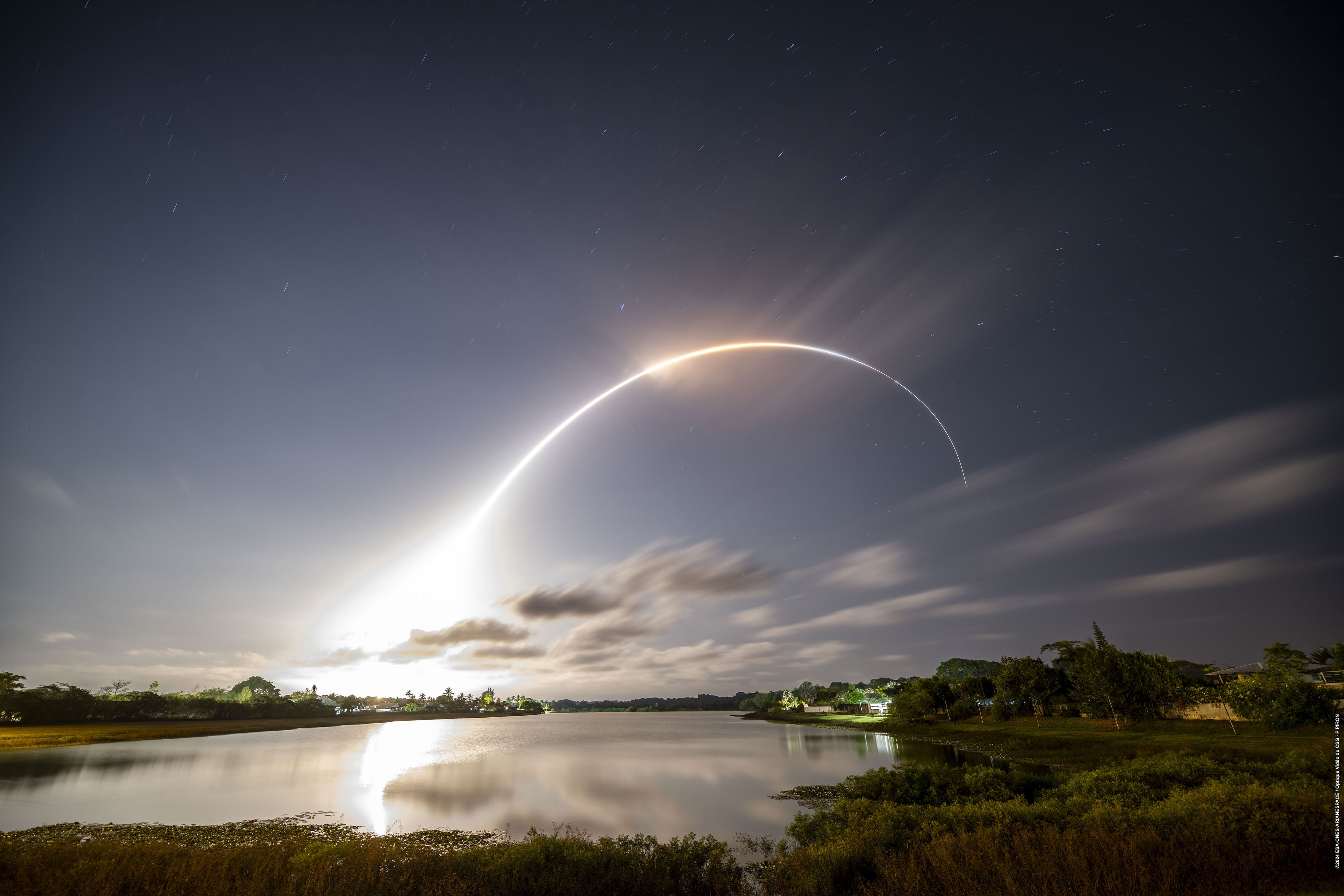 La trajectoire lumineuse de Vega photographiée en pause longue au dessus d'un plan d'eau